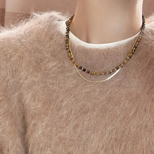 Close-up of double-layer necklace with gold snake chain and brown tiger eye beads
