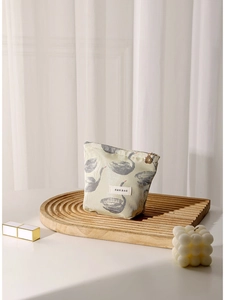 Swan pattern jacquard makeup bag with floral zipper on a minimalist wooden tray