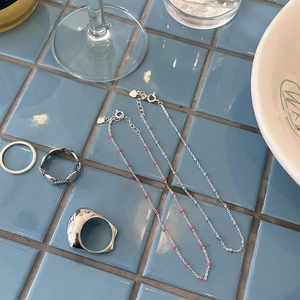 Minimalist 925 sterling silver beaded bracelet and rings set on blue tiles background