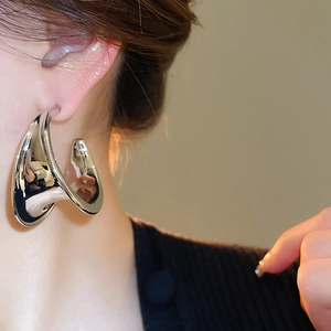 Close-up of exaggerated silver twisted C-shaped earrings with a metallic finish