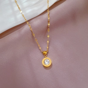 Close-up of gold titanium necklace with roman numeral pendant and zircon stone
