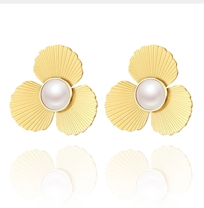 Détail de boucles d'oreilles fleur à trois pétales dorés avec perle blanche centrale