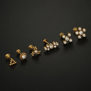 Macro shot of 16G gold surgical steel ear piercing set with clear zircon stones on black