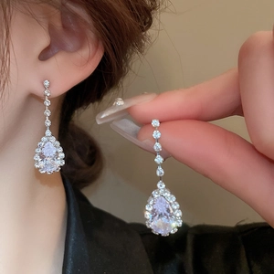Detail of silver teardrop earrings with sparkling crystals held by hand for a close view