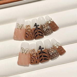 Close-up of handmade press-on nails with 3D butterfly, bear icons and tiger patterns