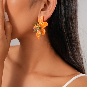 Close-up of orange resin flower earring with green and purple beaded core on model
