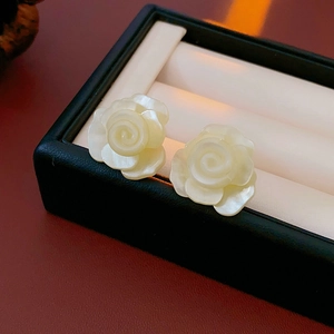 Gros plan de boucles d'oreilles roses en résine blanche avec éclat de nacre en boîte