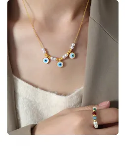 Detail of gold necklace and ring set with pearls and blue evil eye charms on a model