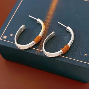 Matte silver oval hoop earrings with brown leather trim in a luxury jewelry gift box