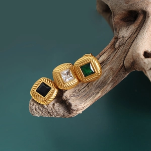 Vintage gold square stud earrings with emerald and black gems on wood base