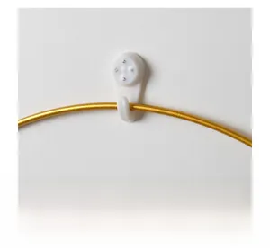 Close-up of a white plastic non-marking wall hook holding a gold iron wall decoration