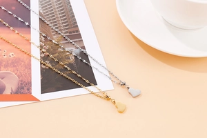 Close-up of heart-shaped titanium steel necklaces in gold and silver on a desk