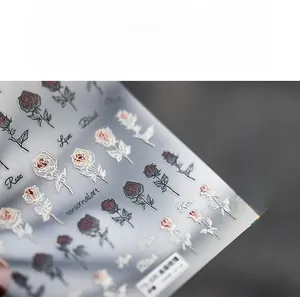 Gros plan détaillé de stickers d'ongles 5D avec roses rouges et détails dorés fins