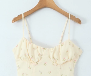 Detail of light yellow floral dress featuring delicate straps and ruched sweetheart neckline