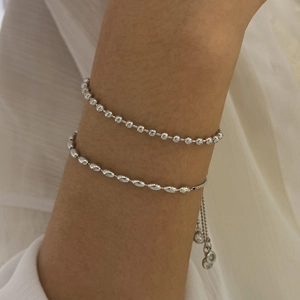 Close-up of silver beaded and oval link bracelets with adjustable clasps on a wrist