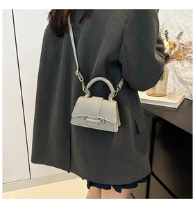 Sac à bandoulière argenté tressé porté avec un blazer gris pour un look chic moderne