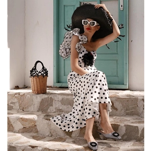 Close-up of retro polka dot swimsuit with ruffle one-shoulder design in a beach setting
