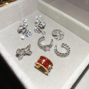 Detailed close-up of zircon bow ear cuffs and earrings set on a velvet display tray