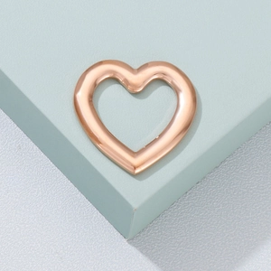 Elegant rose gold hollow heart-shaped metal accessory on a minimalist pedestal