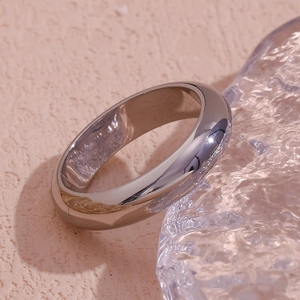 Detailed close-up of polished silver minimalist thick band ring on textured surface