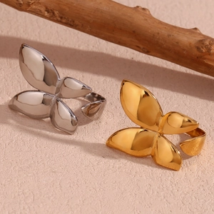 Detail of butterfly open rings in gold and silver finish on pink textured surface