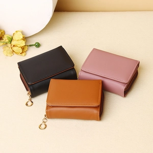 Detailed view of compact tri-fold leather wallets in black, pink and brown with gold ring zippers