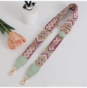 Detail of geometric weave purse strap with green leather ends and gold metal hooks