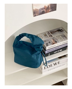 Détail du sac baguette en nylon bleu sarcelle avec poignée nouée et cordon latéral