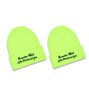 Neon green knit beanie featuring a black No Matter embroidery in a flat lay view