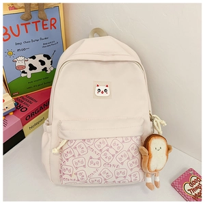 Detail of cream canvas school bag with cute cat print and plush toast accessory