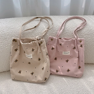Détail de sacs cabas en velours côtelé avec motifs ours et fermoir aimanté en métal
