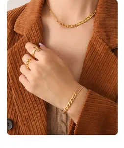 Detailed view of layered gold chain necklaces and bracelets worn with a corduroy jacket