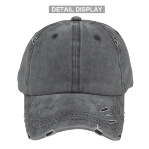 Macro detail of dark grey washed baseball cap showing distressed torn hole and vintage texture