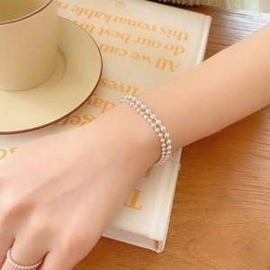 Minimalist double-layered S925 silver bead bracelet and matching ring on a model's hand