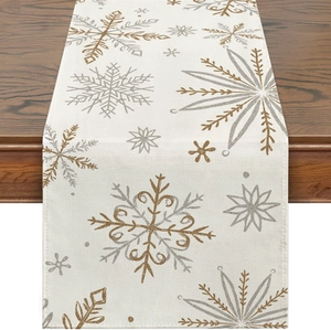 Macro detail of winter table runner with gold and silver snowflake patterns on beige linen