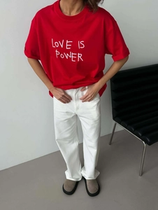 Oversized red t-shirt with Love Is Power print paired with white pants and casual shoes
