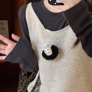 Detail of creative plush sheep brooch on a knitted vest with soft wool texture