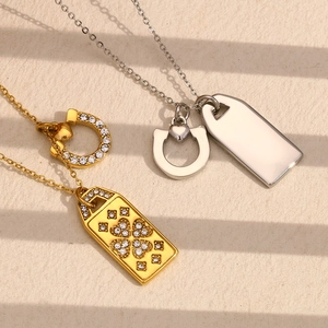 Detail of horse shoe pendant necklaces in gold and silver finish with clover crystal accents