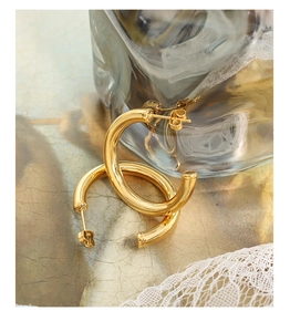 Detailed close-up of 18K gold plated C-shaped hollow hoop earrings on vintage lace background