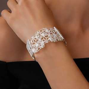 Detailed macro view of wide silver floral hollow cuff bracelet with intricate filigree texture
