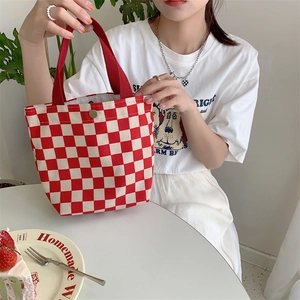 Detail of red and white checkered canvas tote bag with a secure metal magnetic closure