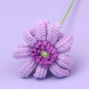Detailaufnahme einer handgehäkelten lila Gerbera-Blume mit grünem Stiel aus Wolle