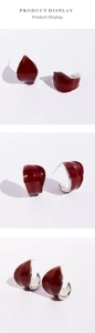 Macro detail of wine red enamel leaf earrings with irregular curved silver-tone metal