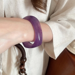 Close-up of a wide purple resin bangle with marble texture worn on the wrist