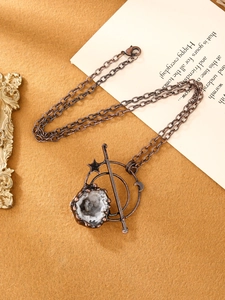Gedetailleerde close-up van de bronzen dubbele maan hanger met ruw kristal en vintage textuur