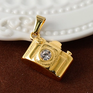 Macro shot of gold-plated camera pendant with sparkling crystal inlay on a soft background