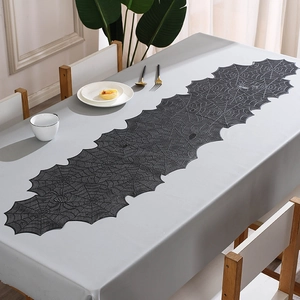 Detail of black spider web lace table runner with intricate hollowed-out patterns