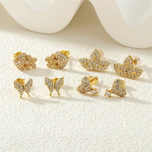 Detailed view of four pairs of gold clover, butterfly, and heart stud earrings with zircons