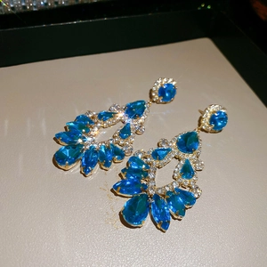 Macro shot of luxury gold-plated drop earrings featuring teardrop sea blue gemstones