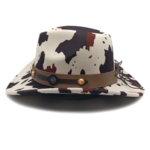 Detail of cow print western cowboy hat with brown leather band and gold star rivet